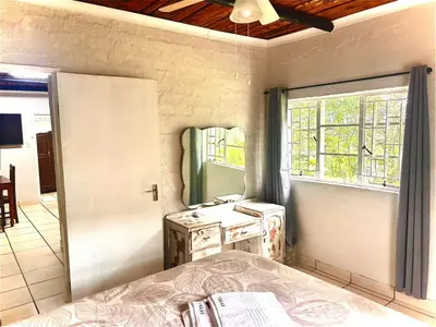 a bedroom with a bed and a sink and a window at Kanaan Guest Farm in Hazyview