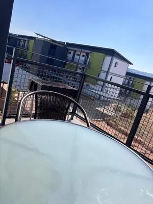 a table on a balcony with a building in the background at Grey Heaven Retreat in Boschrand