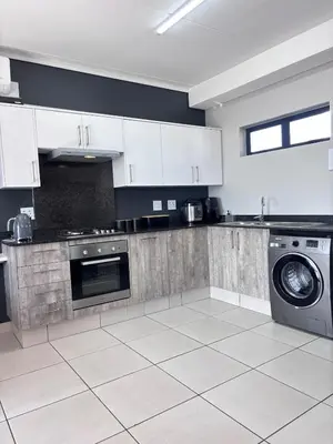a kitchen with white cabinets and a washing machine at Grey Heaven Retreat in Boschrand