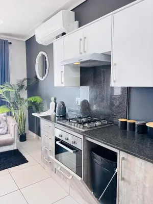 a kitchen with white cabinets and a stove at Grey Heaven Retreat in Boschrand