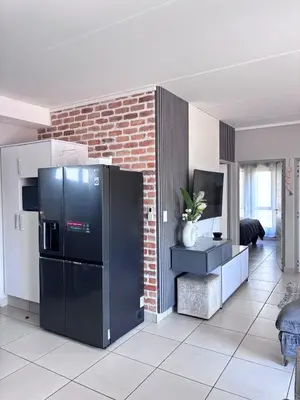 a kitchen with a black refrigerator and a brick wall at Grey Heaven Retreat in Boschrand