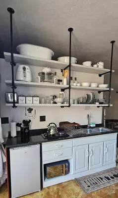 a kitchen with white shelves and a counter top at Upstairs R-3 Self Catering Unit in White River
