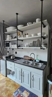 a kitchen with white cabinets and a sink and shelves at Upstairs R-3 Self Catering Unit in White River