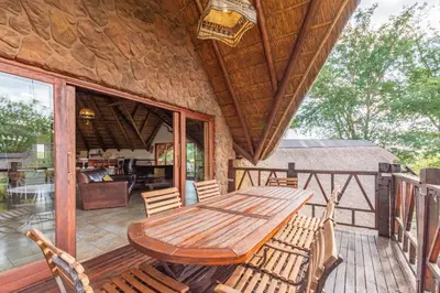 a wooden table and chairs on the deck of a cabin at Zebula 4-bedroom, 12 sleeper - 63 in Warmbaths