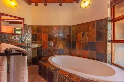 a bathroom with a tub and a mirror at Zebula 4-bedroom, 12 sleeper - 63 in Warmbaths
