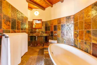 a bathroom with a tub and a tiled wall at Zebula 4-bedroom, 12 sleeper - 63 in Warmbaths