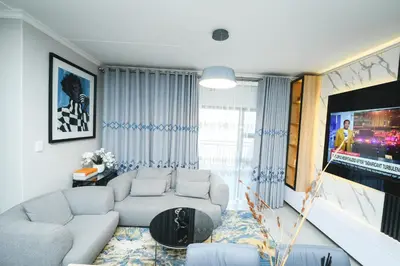 a living room with a couch and a tv at Waterfall luxe apartment in Kyalami