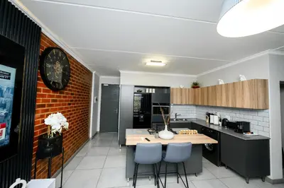a kitchen with a wooden table and blue chairs at Waterfall luxe apartment in Kyalami