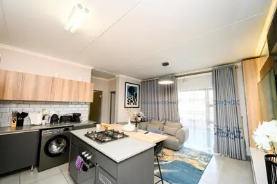 a kitchen with a stove top oven next to a living room at Waterfall luxe apartment in Kyalami