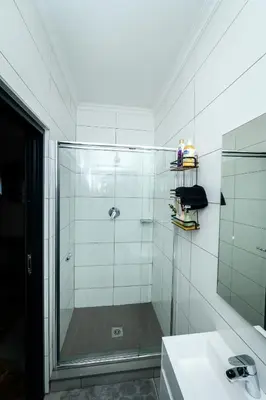 a glass shower in a bathroom with a sink at Waterfall luxe apartment in Kyalami