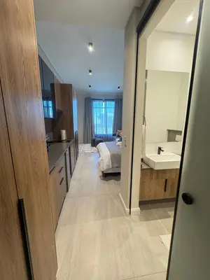 a bathroom with a bed and a sink and a mirror at Studio Sol at Trilogy in Pretoria