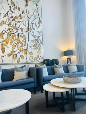 a living room with a blue couch and two tables at Studio Sol at Trilogy in Pretoria