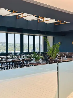 a restaurant with tables and chairs and windows at Studio Sol at Trilogy in Pretoria