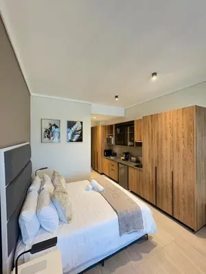 a bedroom with a large bed and a kitchen at Studio Sol at Trilogy in Pretoria