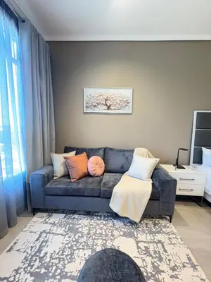 a living room with a blue couch with pillows at Studio Sol at Trilogy in Pretoria