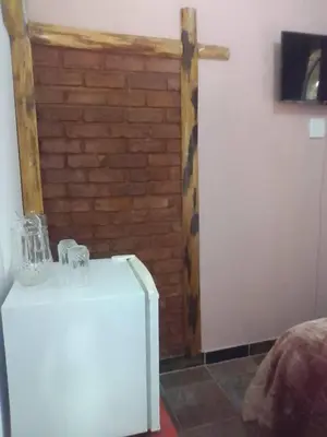 a white refrigerator in a room with a brick wall at Mountain Guesthouse in Pretoria