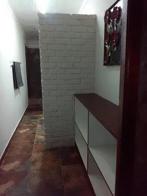 a room with a white brick wall and a cabinet at Mountain Guesthouse in Pretoria