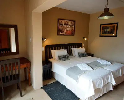 a bedroom with two beds and a table and a mirror at Tau @ Kruger in Marloth Park