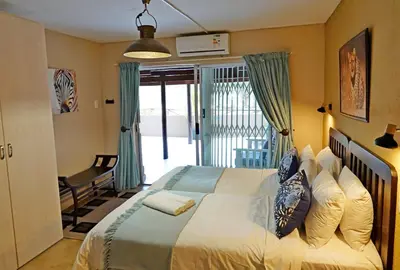 a bedroom with a bed and a chair and a window at Tau @ Kruger in Marloth Park