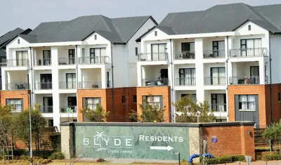 a large white apartment building with red brick at Modern 2BR Retreat at The Blyde in Pretoria