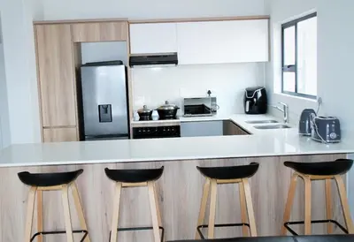 a kitchen with a counter with three bar stools at Modern 2BR Retreat at The Blyde in Pretoria