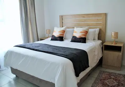 a bedroom with a large bed with white sheets and pillows at Modern 2BR Retreat at The Blyde in Pretoria