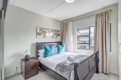 a bedroom with a bed with blue pillows and a window at 225 The Woods, Kyalami in Midrand