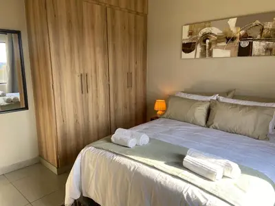 a bedroom with a bed with towels on it at Warm, Homely Apartment - 5min Away Menlyn Main in Pretoria