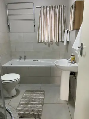 a bathroom with a tub and a toilet and a sink at Warm, Homely Apartment - 5min Away Menlyn Main in Pretoria