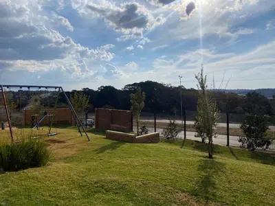 a park with a swing set in the grass at Warm, Homely Apartment - 5min Away Menlyn Main in Pretoria