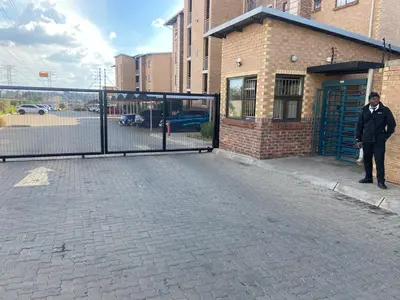 a man standing in front of a gate on a street at Warm, Homely Apartment - 5min Away Menlyn Main in Pretoria