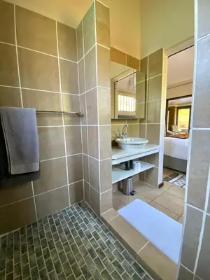 a bathroom with a shower with a sink and a mirror at Park View - Creature comforts in nature in Marloth Park