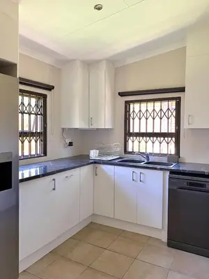 a kitchen with white cabinets and a black dishwasher at Park View - Creature comforts in nature in Marloth Park