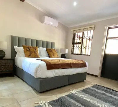 a bedroom with a large bed with a gray headboard at Park View - Creature comforts in nature in Marloth Park