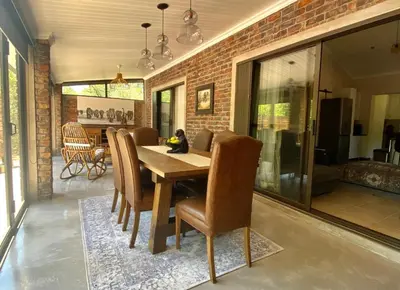 a dining room with a wooden table and chairs at Park View - Creature comforts in nature in Marloth Park