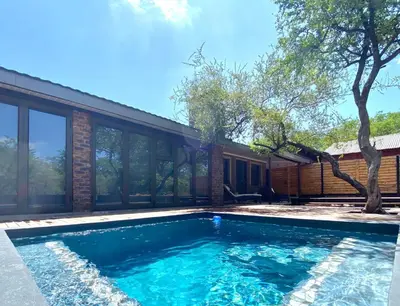 a swimming pool in front of a house at Park View - Creature comforts in nature in Marloth Park