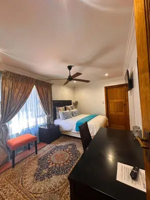a hotel room with a bed and a desk and a table at Tsheryl's Residence in Centurion