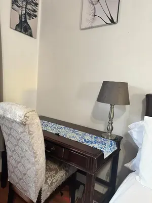 a bedroom with a desk and a chair and a lamp at Tsheryl's Residence in Centurion