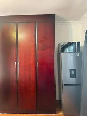 a large wooden cabinet next to a refrigerator at Tsheryl's Residence in Centurion