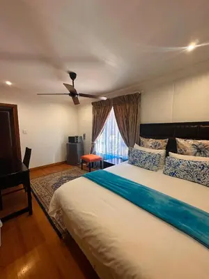 a bedroom with a large bed with a ceiling fan at Tsheryl's Residence in Centurion