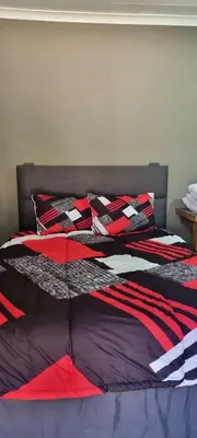 a bed with red and black sheets and pillows at Cammys in Secunda