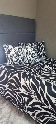 a bed with a black and white blanket and pillows at Cammys in Secunda