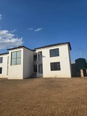 a white house with a brick driveway at Limpopo LidoSystem Lodge