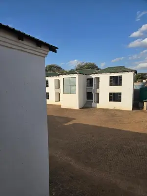 a row of white buildings in a parking lot at Limpopo LidoSystem Lodge