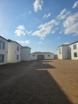 a row of white buildings on a brick road at Limpopo LidoSystem Lodge