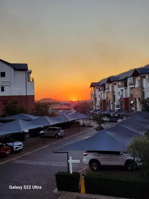 a car parked in a parking lot with a sunset in the background at WeAreTogetherLuxuryApartment in Pretoria