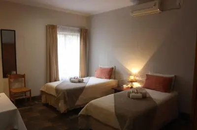 a hotel room with two beds and a window at Ilane Guesthouse in Nelspruit