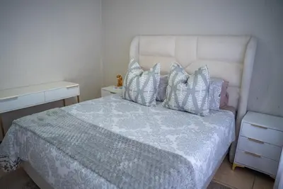 a bedroom with a white bed with four pillows at Modern Tranquility in Benoni