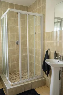 a shower with a glass door next to a sink at Modern Tranquility in Benoni
