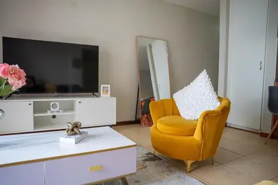 a living room with a yellow chair and a tv at Modern Tranquility in Benoni